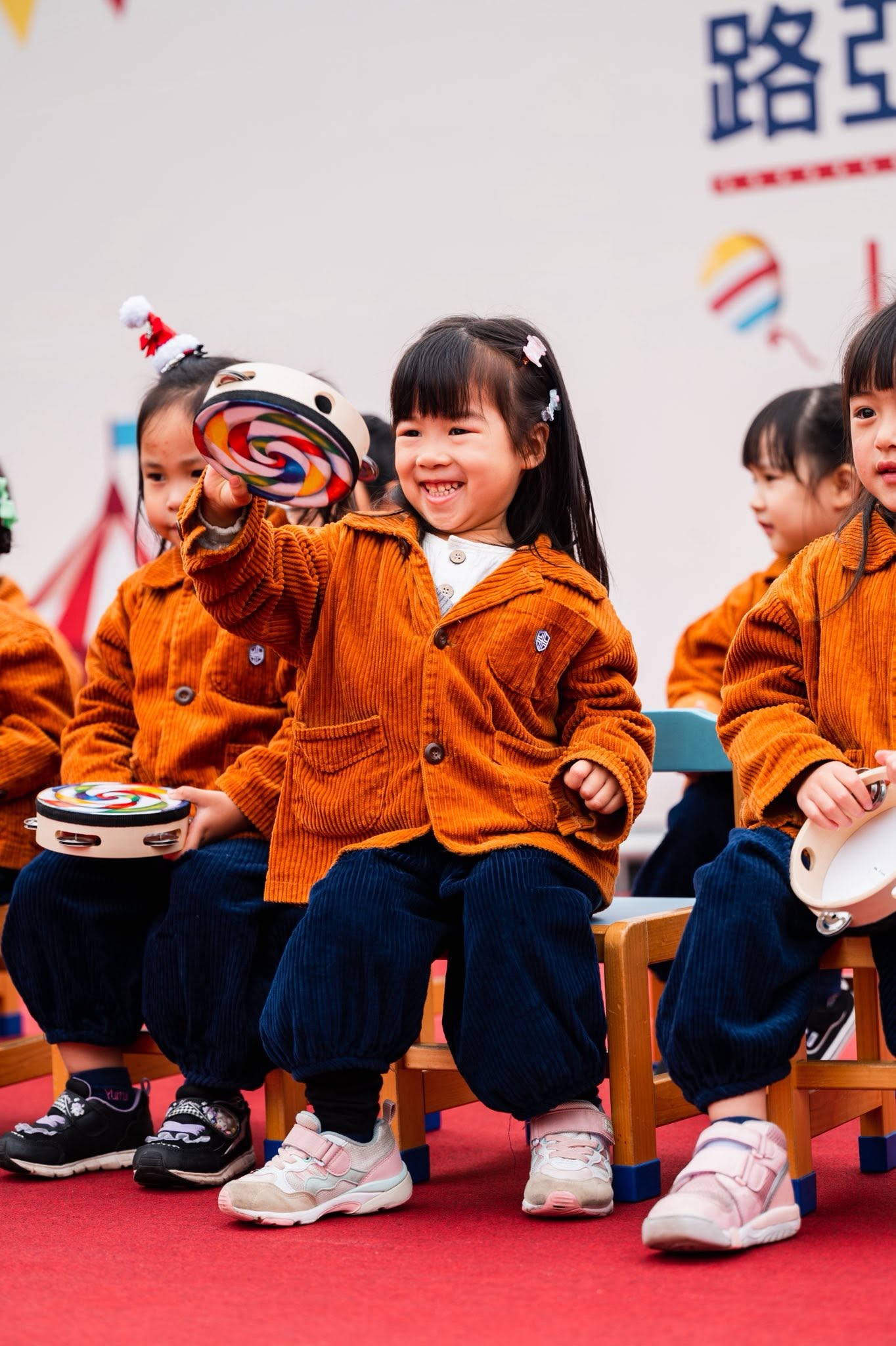 孩子在校慶表演中拿著鈴鼓開心演出
