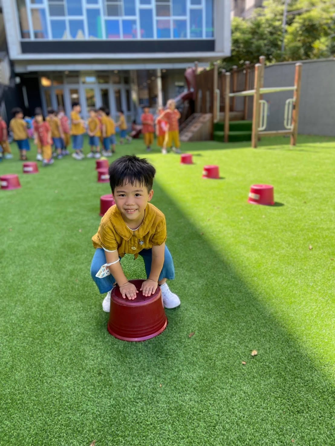 孩子在園區草地上搬動踏桶，準備進行平衡遊戲