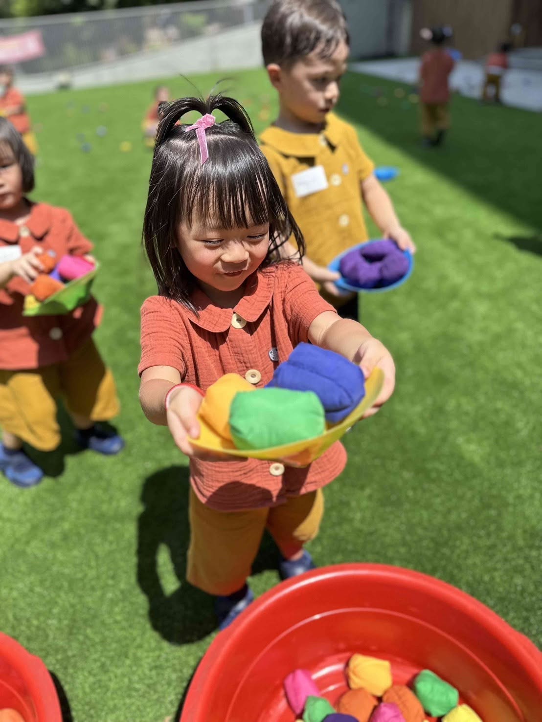 孩子端著裝滿沙包的盤子，參與戶外遊戲