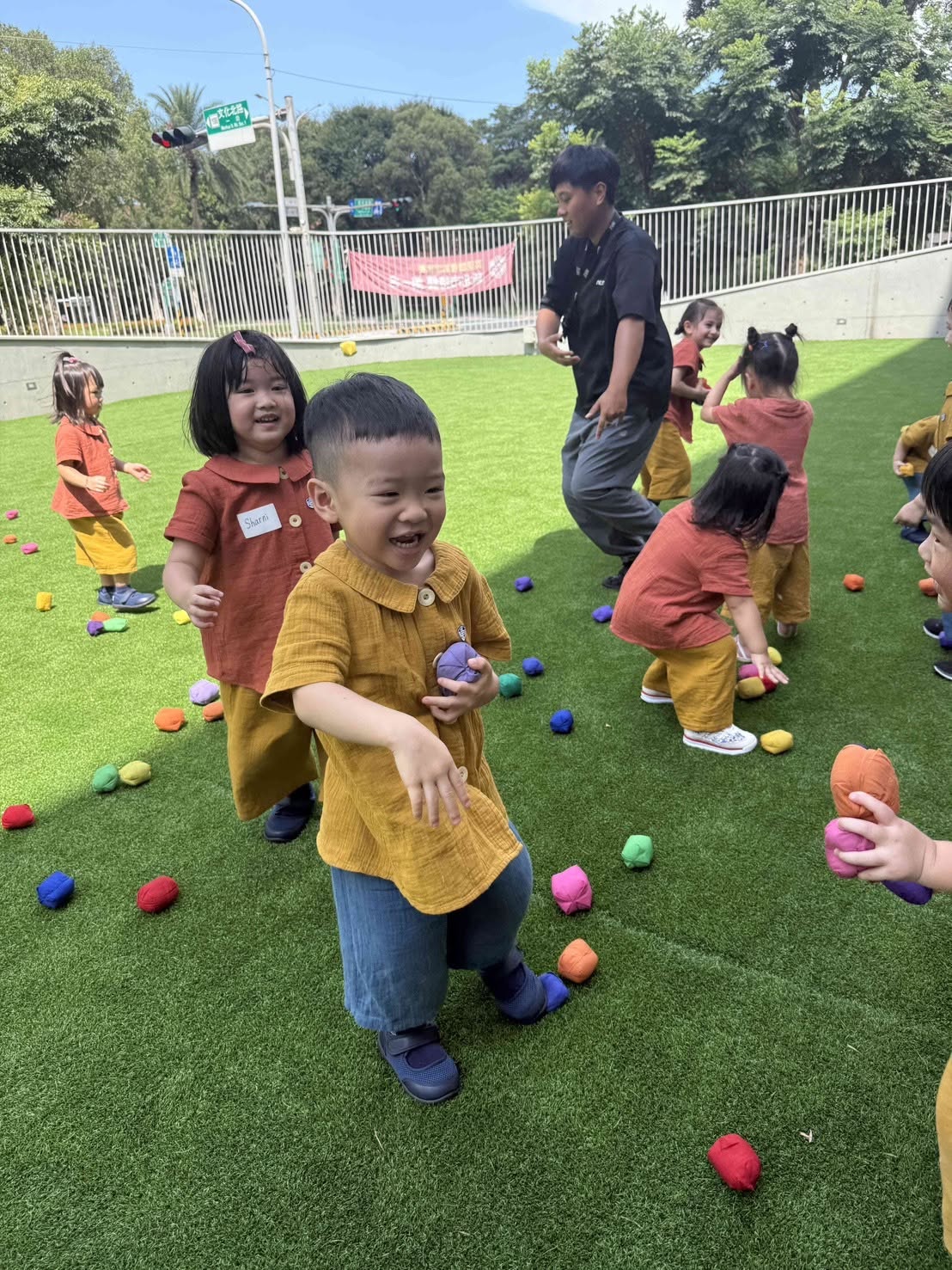 孩子們在草地上進行沙包遊戲，老師在旁陪伴