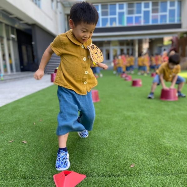 孩子在草地上沿著標記點練習跳躍