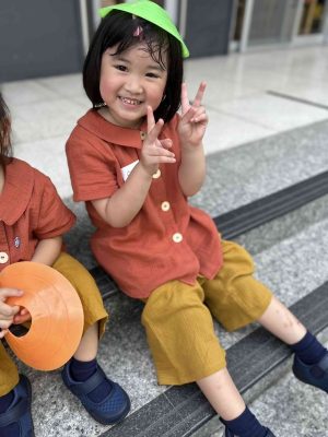 孩子坐在戶外階梯上開心比出手勢